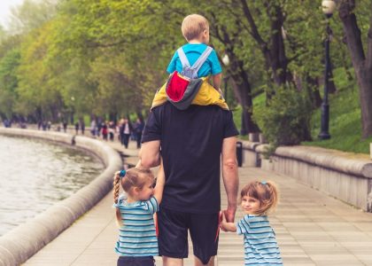 the father walks with three kids in the park