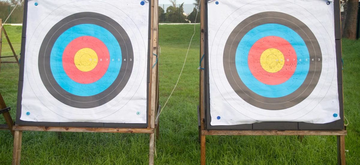 Two colorful archery targets standing on a green field under clear skies, perfect for outdoor sports enthusiasts.