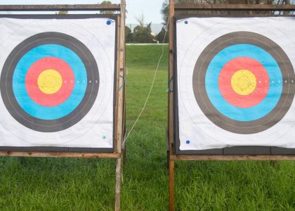 Two colorful archery targets standing on a green field under clear skies, perfect for outdoor sports enthusiasts.